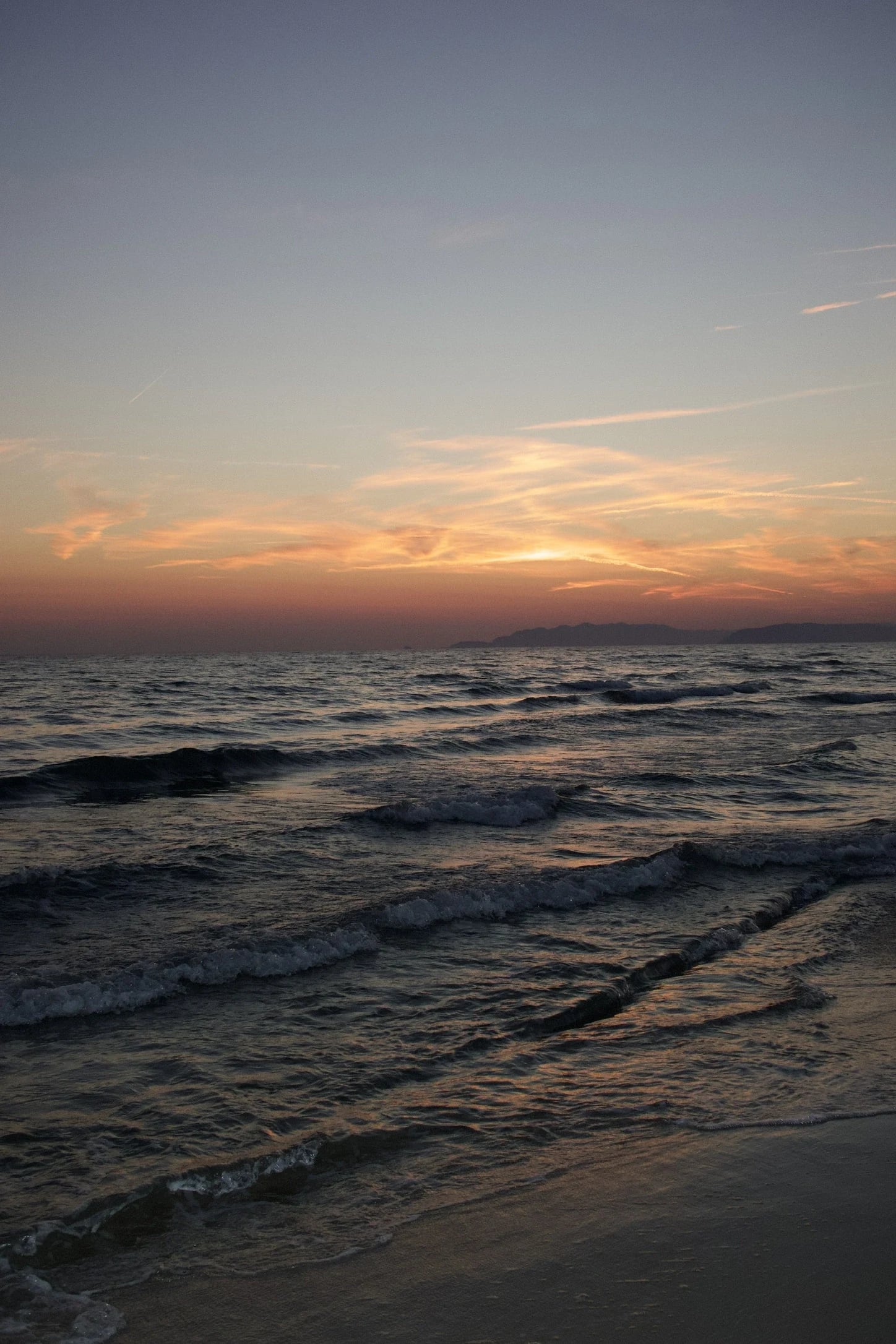 Waves at dusk under a warm sunset sky