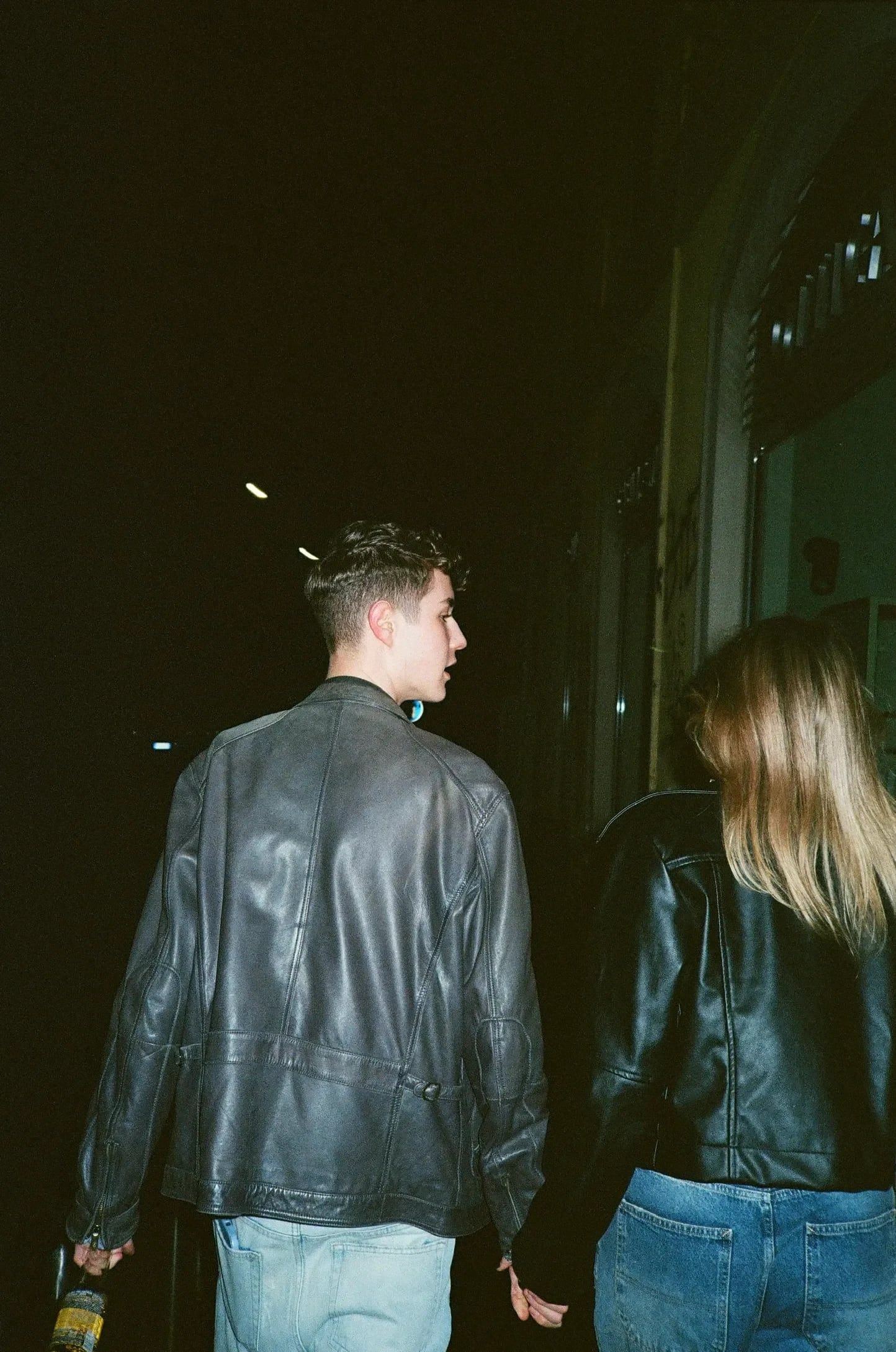 Two figures walking through the city at night